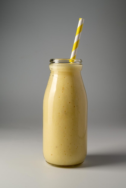 Bottle of mango banana and yoghurt smoothie with a straw