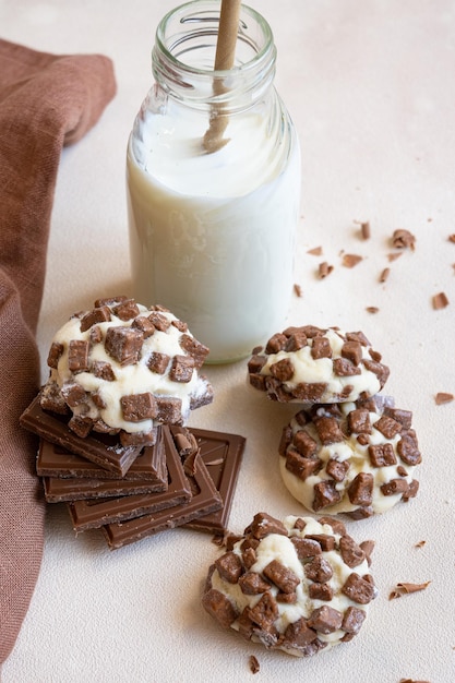 A bottle of milk with chocolate cookies and a chocolate chip cookie on top.