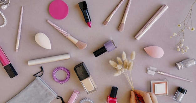 A bottle of nail polish is on a table with other makeup including a pink and black nail polish.