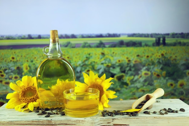 A bottle of oil, fresh sunflower flowers and seeds on the table, organic products, harvest