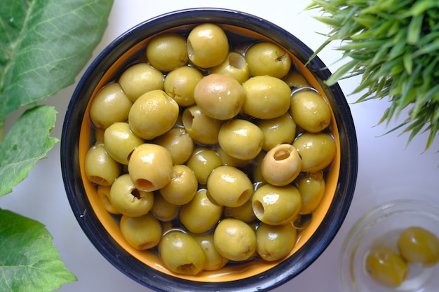 Bottle of olive oil and fresh olive in a container on table