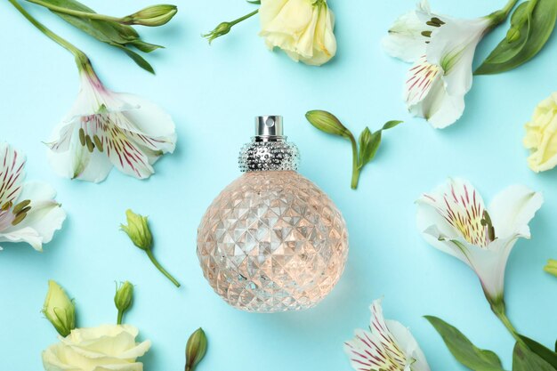 Bottle of perfume and flowers on blue background