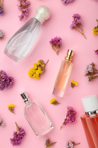 Bottle of perfume with flowers on pink table.