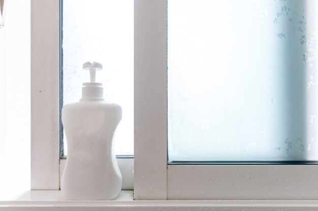 Bottle pump of soap or shampoo on the edge of bathroom windows.