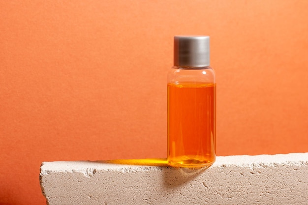 A bottle of serum and essential cosmetic oil on a podium with shadows in the background Spa product for skin care