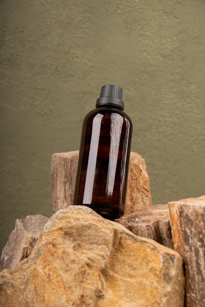 Photo a bottle of serum liquid sits on top of a pile of rocks