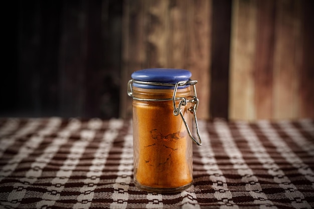 Bottle of spicy powder on rustic wooden background