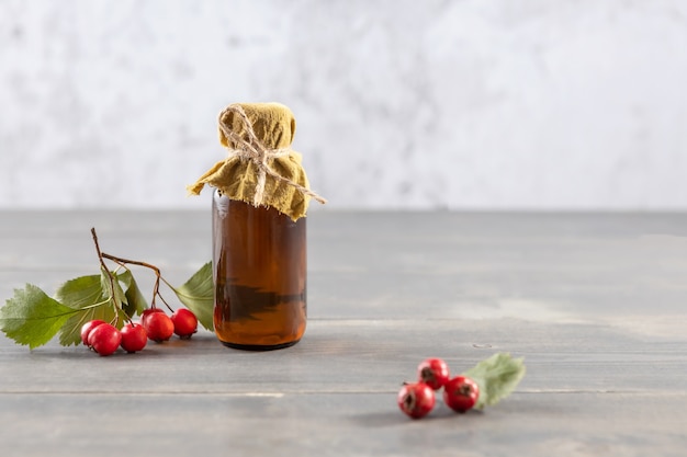 Bottle of tincture of hawthorn berries and fresh berries