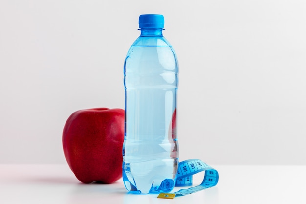 Bottle of water, measuring tape and fresh apple on the table