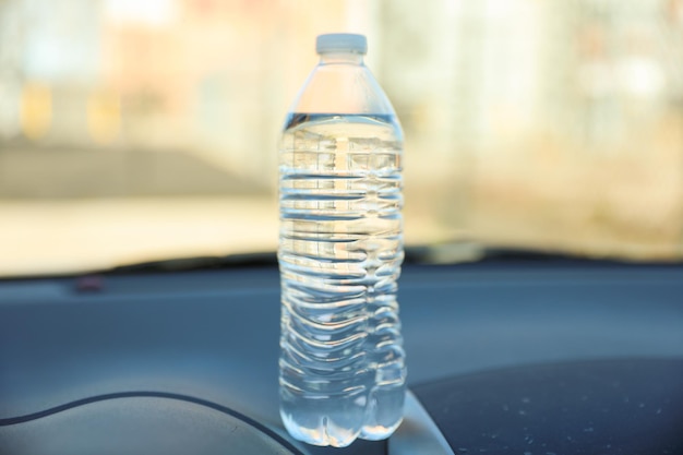 A bottle of water sits on a dashboard.