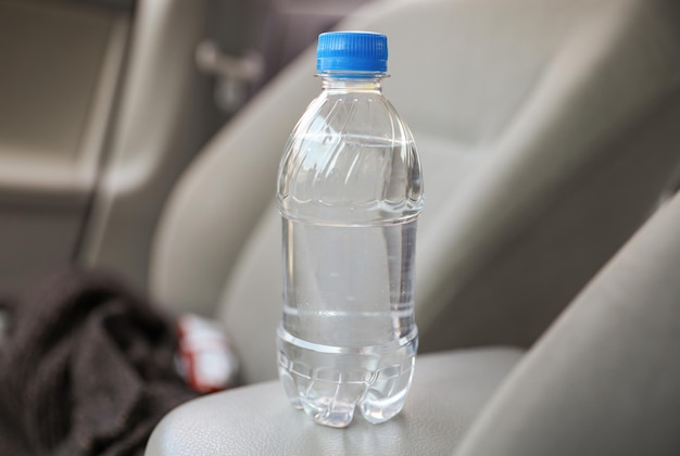 A bottle of water sits on a seat of a car.