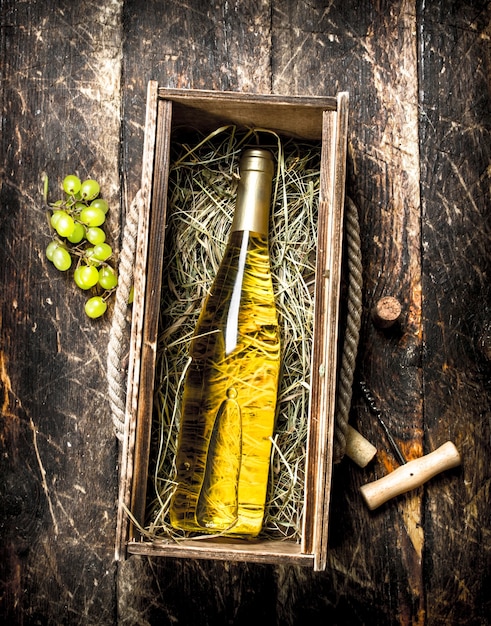 bottle of white wine in an old box. On a wooden background.