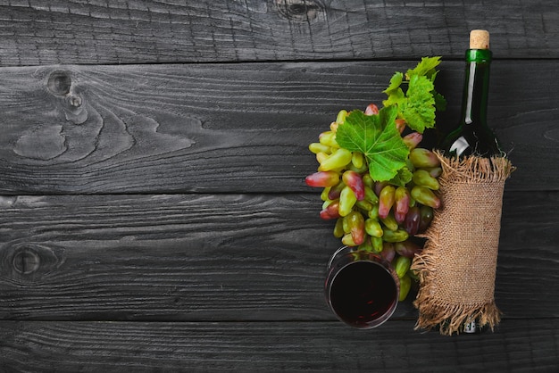 A bottle of wine and grapes On a wooden background Top view Free space for your text