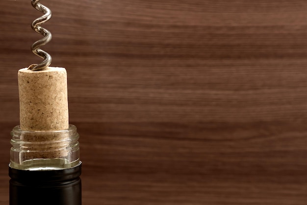 Bottle of wine with corkscrew on wooden background