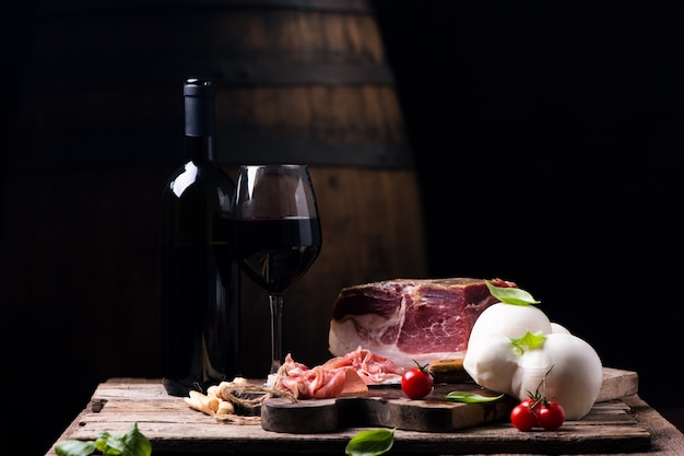 Bottle of wine with a glass on a table with rustic traditional italian food.Fresh tipical italian lifestyle