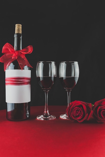 Bottle of wine with two glasses and a rose on a table