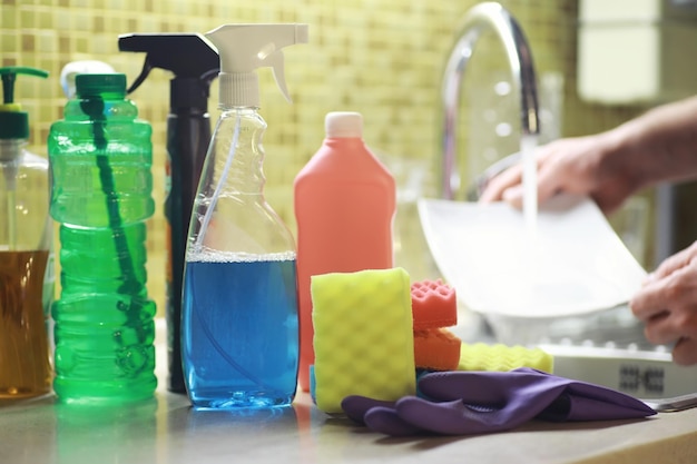 A bottle with an environmentally friendly dishwashing detergent on the background of a housewife washing dishes