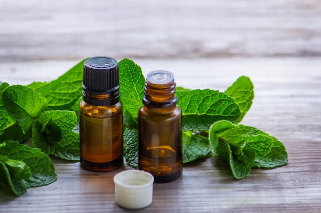 Bottle with essential oil and mint isolated on a light background