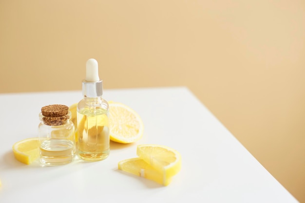 Bottle with lemon essential oil with lemon slices on table Cosmetic citrus oil or serum Natural medicine concept Aromatherapy