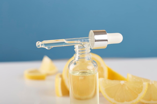 Bottle with lemon essential oil with lemon slices on table Cosmetic citrus oil or serum Natural medicine concept Aromatherapy