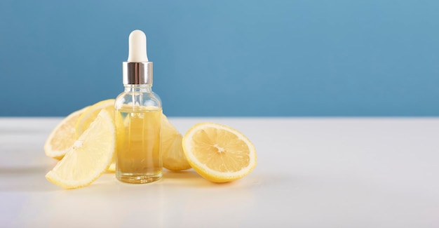 Bottle with lemon essential oil with lemon slices on table Cosmetic citrus oil or serum Natural medicine concept Aromatherapy