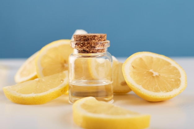 Bottle with lemon essential oil with lemon slices on table Cosmetic citrus oil or serum Natural medicine concept Aromatherapy