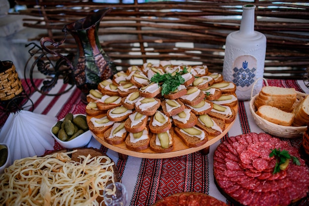 Bottle with vodka and plates with pickled vegetables and meat stand on the table