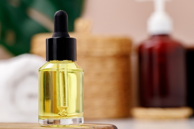 Bottle of yellow cosmetic oil on wooden tray close up photo