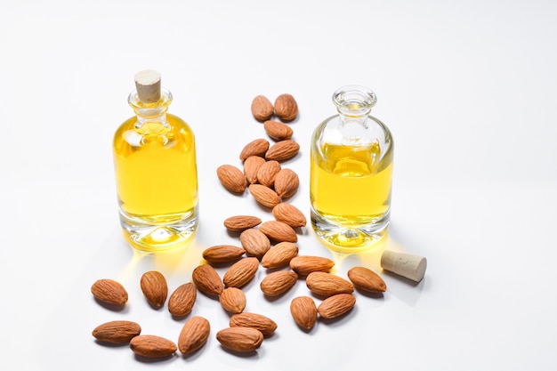 Bottles of almond oil and almonds on white background copyspace