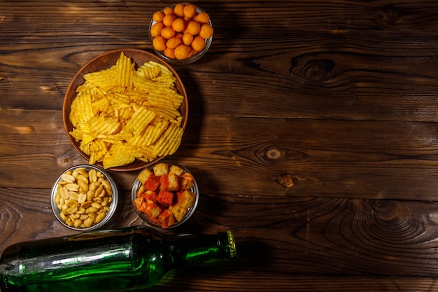 Bottles of beer and various snacks for beer on wooden table