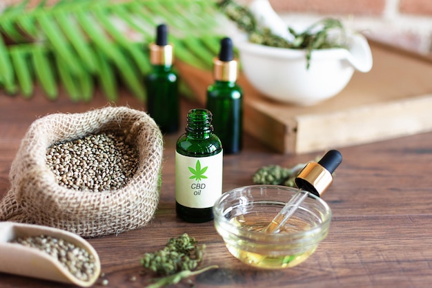 Bottles of hemp oil with cannabis seeds and dry leaves Alternative medicine concept