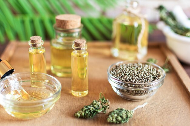 Bottles of hemp oil with cannabis seeds and dry leaves on white Alternative medicine concept