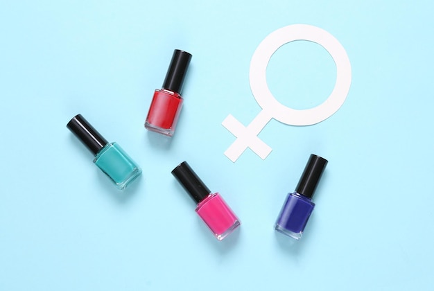 Bottles of nail polish and venus symbol on blue background Top view