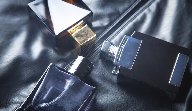 Bottles of perfume on the black leather background.