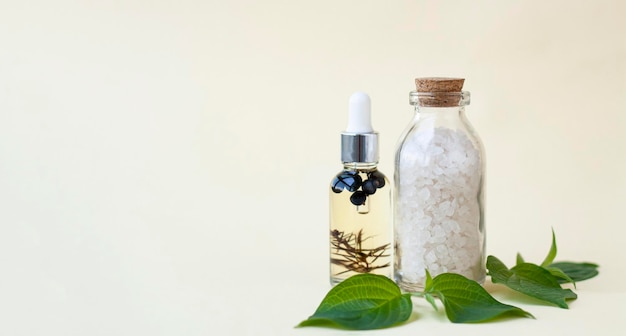 Bottles of sea salt for the bath and body oil a few green leaves Banner