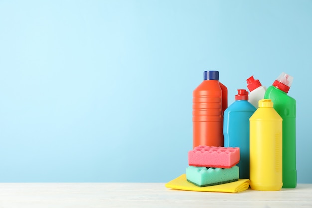 Bottles with detergent and cleaning supplies on blue background, space for text