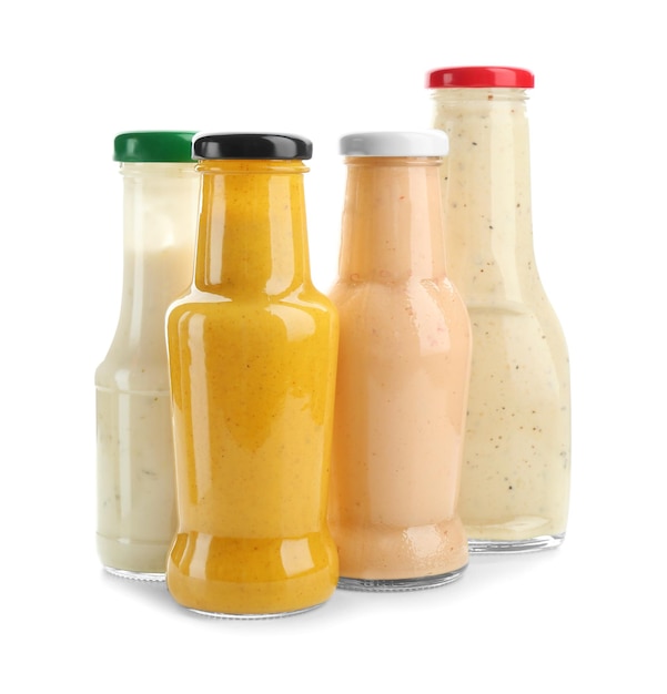 Bottles with different sauces for salad on white background