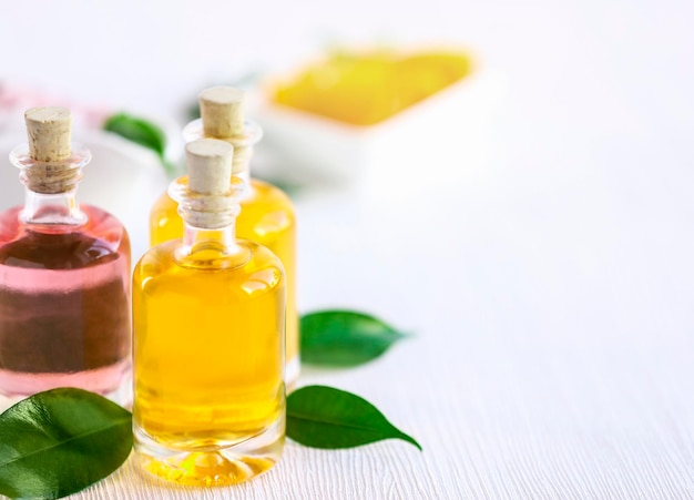 Bottles with essential oil and leaves on wooden table