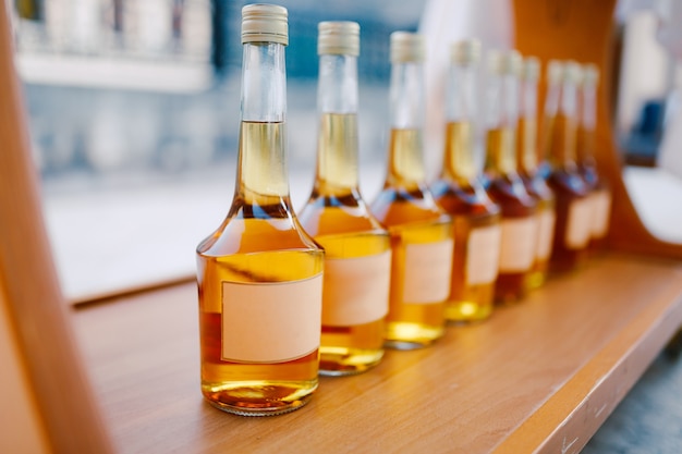 Photo bottles with a golden alcoholic beverage empty labels bottles of rakia are on display in a row