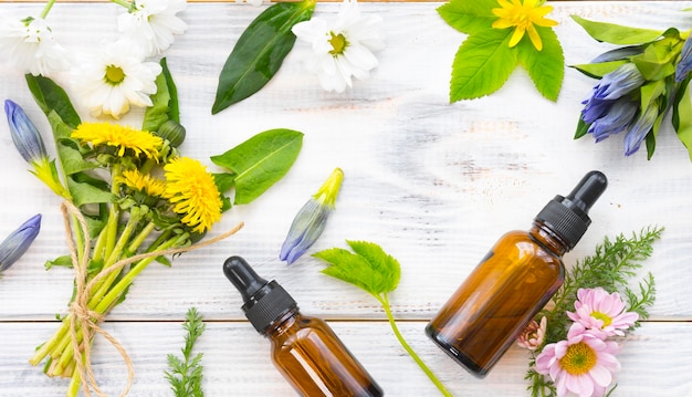 Bottles with natural cosmetics and a variety of leaves and flowers