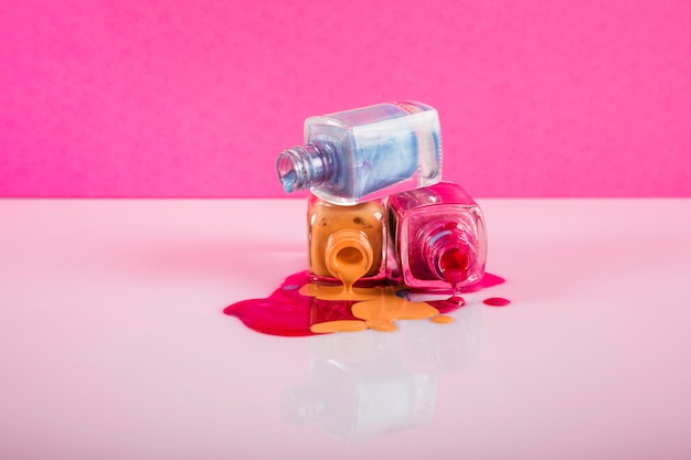 Bottles with spilled nail polish on colorful background