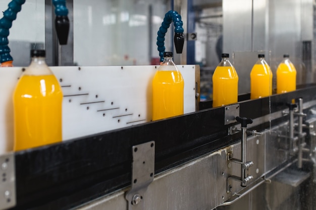 Bottling factory - Orange juice bottling line for processing and bottling juice into bottles. Selective focus.