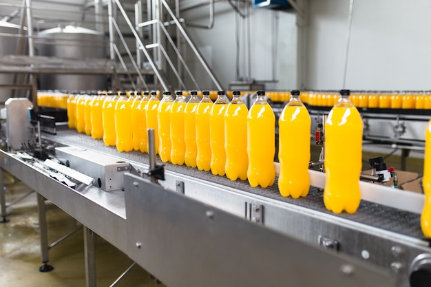 Bottling factory - Orange juice bottling line for processing and bottling juice into bottles. Selective focus.