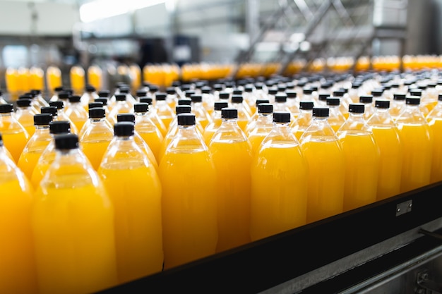 Bottling factory - Orange juice bottling line for processing and bottling juice into bottles. Selective focus.