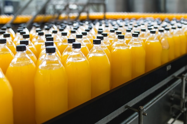 Bottling factory - Orange juice bottling line for processing and bottling juice into bottles. Selective focus.