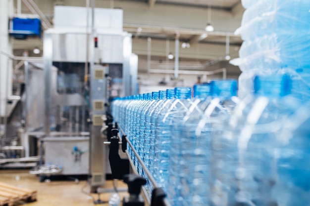 Bottling plant - Water bottling line for processing and bottling pure spring water into blue bottles. Selective focus.