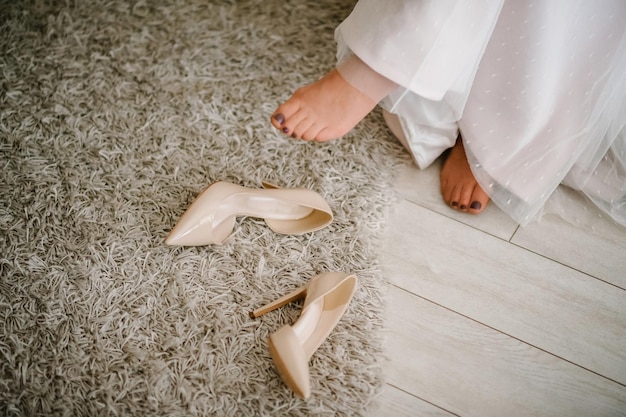 The bottom of the dress beige bride shoes and legs on a wooden floor Part dress dresses Wedding morning meeting bride Stylish shoes close up