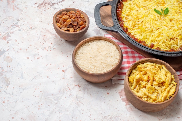 bottom half view tasty plov in big pan dry grapes rice chicken in wooden bowls on table