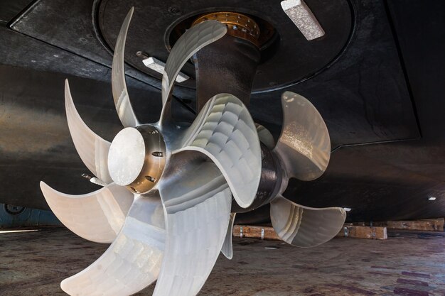 Photo the bottom of a ship supported in dry dock with azimuth propulsion and twin propellers aft