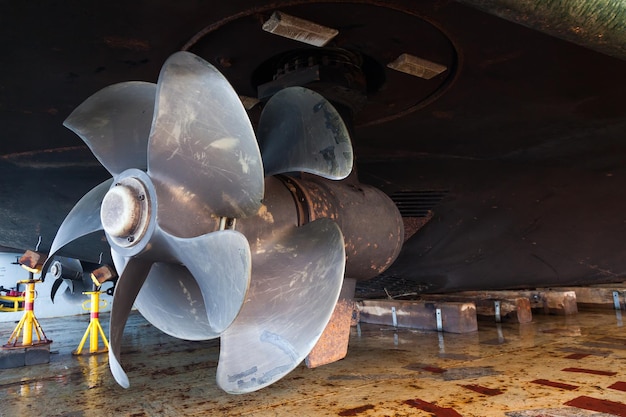 Photo the bottom of a ship supported in dry dock with azimuth propulsion and twin propellers aft